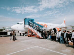 Travelers line up to board a Lion Air airplane at Medan Airport, Indonesia, during a sunny day.