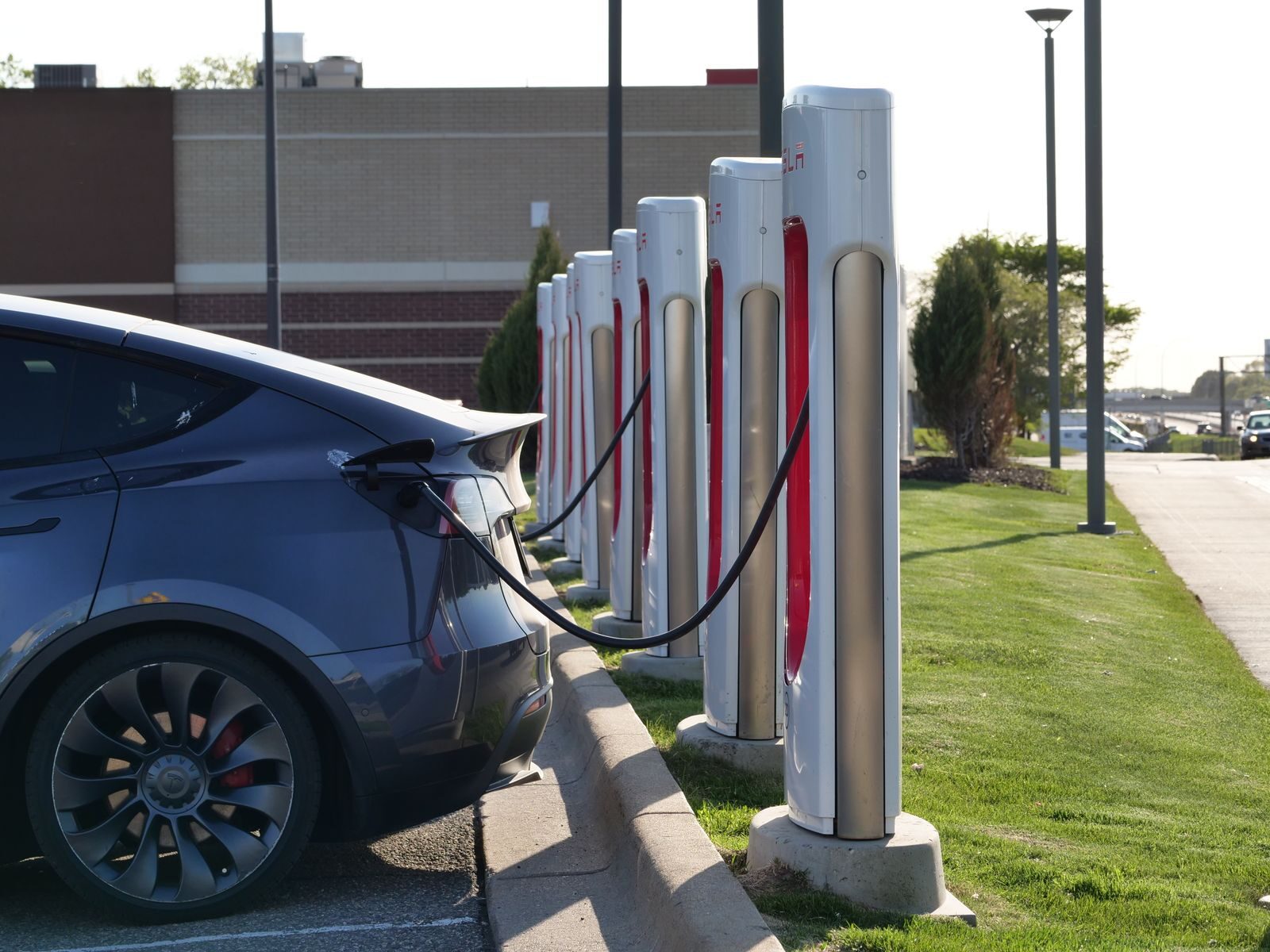 Electric car plugged into a row of charging stations, showcasing modern EV infrastructure.