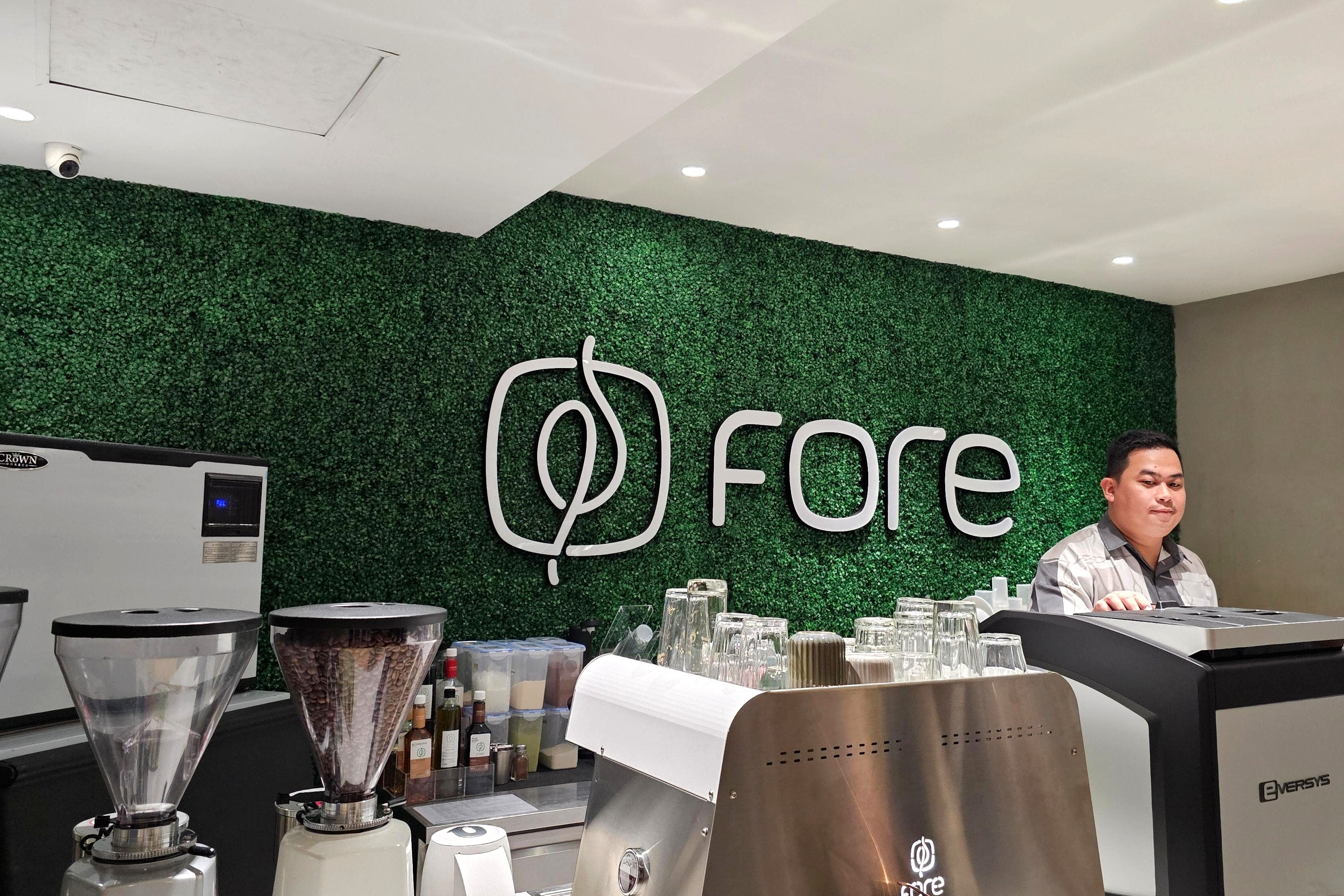 Logo Fore Coffee pada gerai modern dengan suasana ramai pengunjung