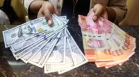 Lembaran uang rupiah dengan latar belakang grafik pergerakan nilai tukar mata uang asing