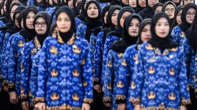 Ilustrasi guru sedang mengerjakan ujian di depan layar komputer di ruang kelas