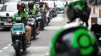 f998bb8a5ec35321f5888cde285895f0.jpg Seorang mitra pengemudi GrabBike sedang mengendarai sepeda motor di jalan raya Jakarta