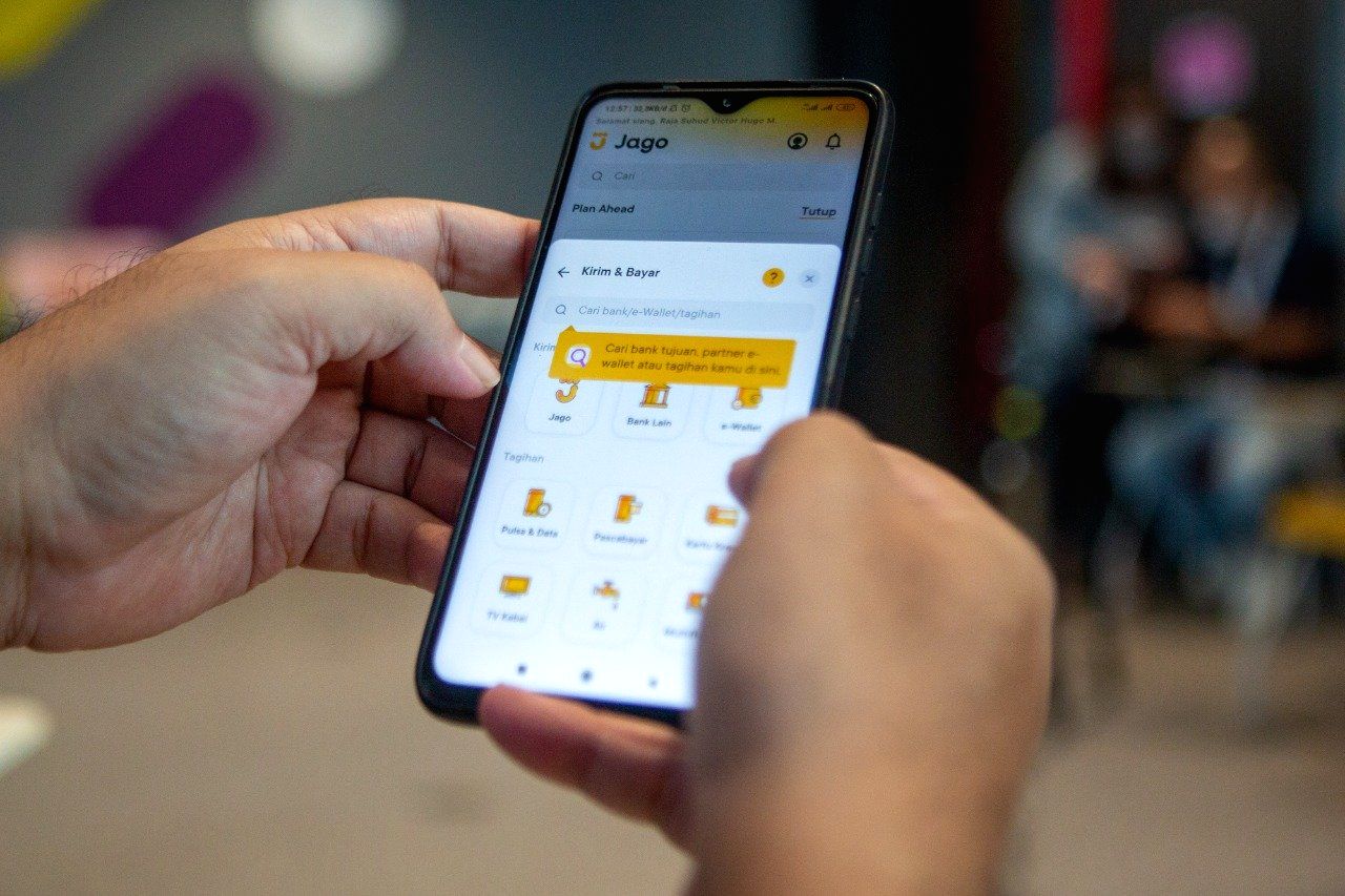 Logo Bank Jago ditampilkan dengan latar belakang konsep investasi emas digital