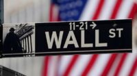 Papan layar elektronik menampilkan pergerakan indeks saham di bursa Wall Street, New York.