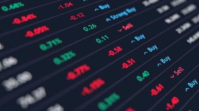 Seorang trader memantau grafik pergerakan harga saham dan forex di layar komputer