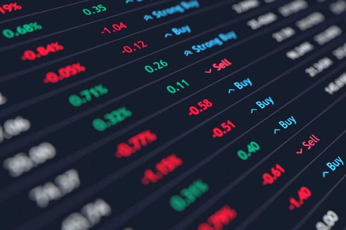 Seorang trader memantau grafik pergerakan harga saham dan forex di layar komputer